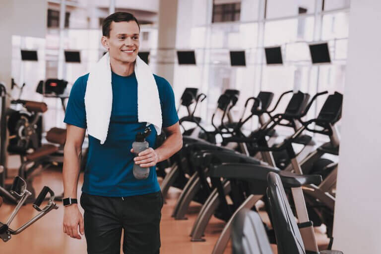 A happy gym member walking next to the elyptical machines