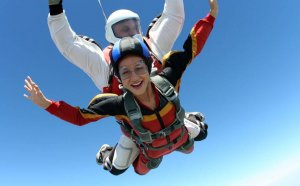 Two people jumpting with a parachute.
