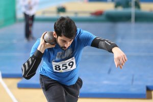 A male athlete about the launch a shot put.