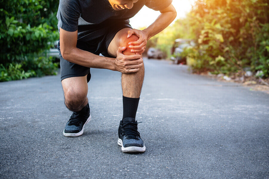 A male runner clutching his knee in pain.
