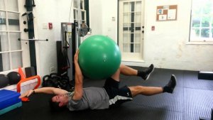 A man in a gym using an exercise ball.