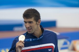 MIchael Phelps holding an Olympic gold medal.
