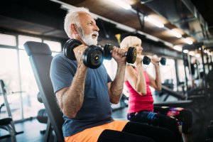 Two elderly people working out in a gym.