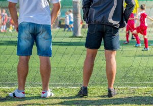 Two parents on the sideline of a soccer game.