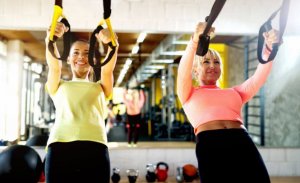 Women exercising at the gym with TRX bands.