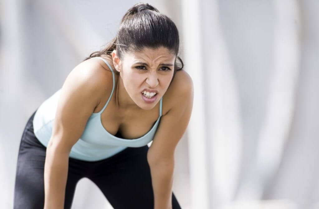A woman feeling tired after a intense workout with a proper warm up to avoid muscle strains