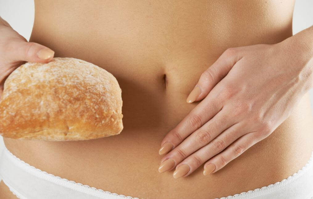 Woman holding a piece of bread next to her abdomen 