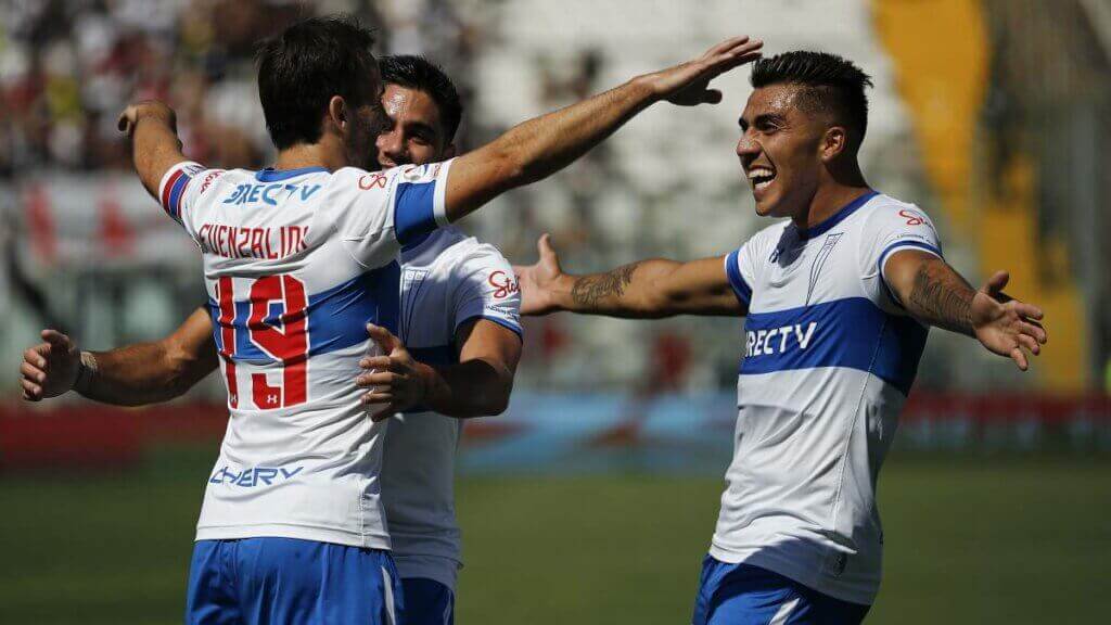 Three players from the Universidad Catolica team hugging after winning one of the classic encounters of Chilean soccer
