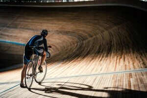 A lone cyclist on a dark velodrome.