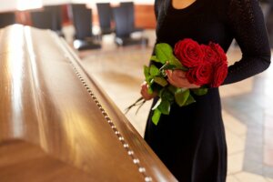 A woman holding flowers over a casket.