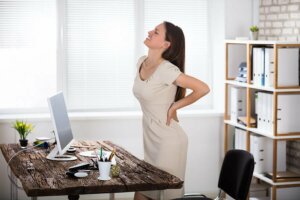 A woman suffering from lower back pain at work.