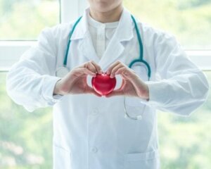 A doctor holding a heart-shaped prop.
