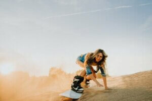 A woman sandboarding, which is just one of many desert adventure sports.