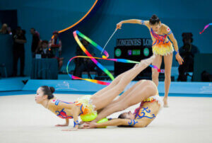 Three rhythmic gymnasts in the middle of a competition.