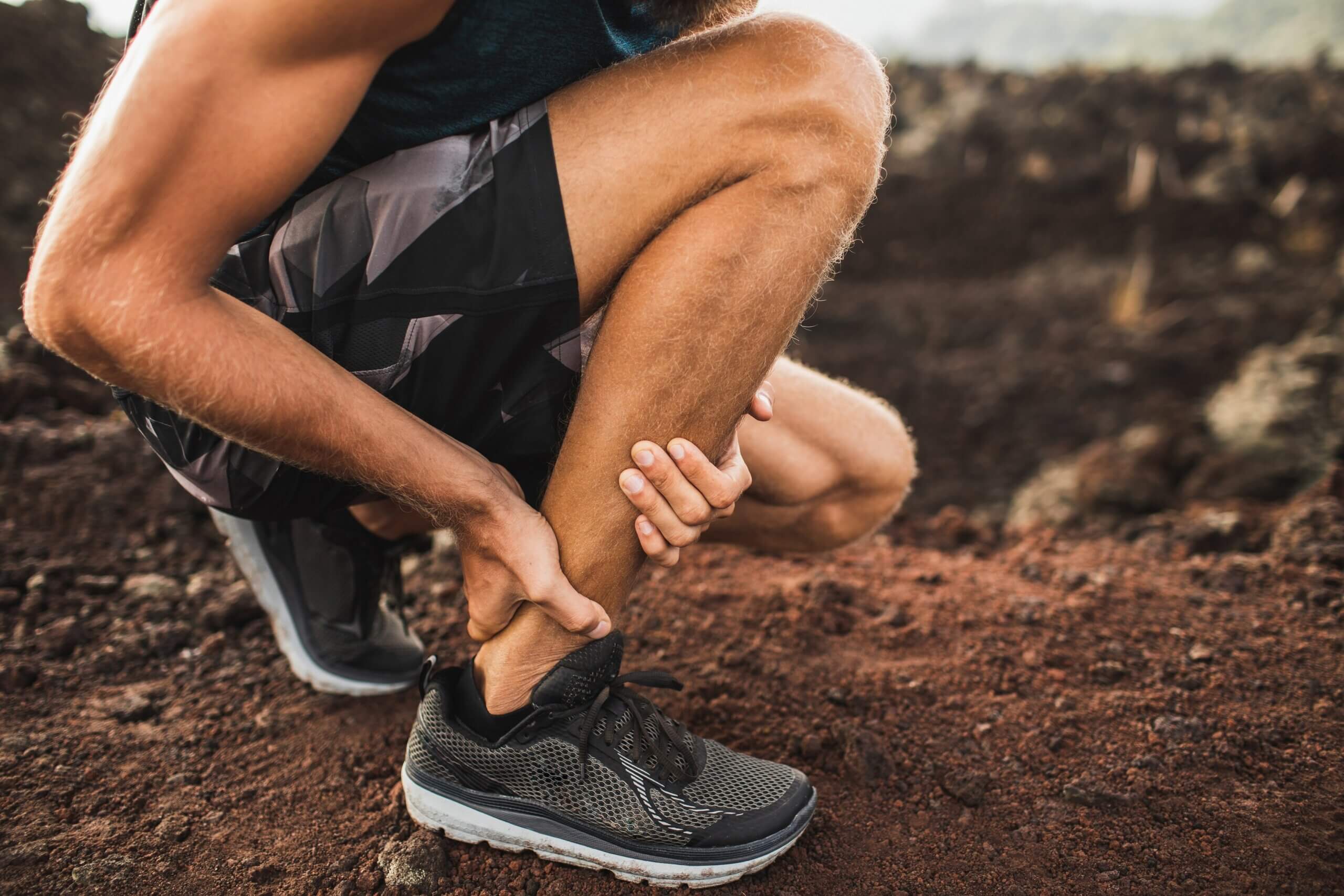 Man holding Achilles tendon by hands close-up and suffering with pain