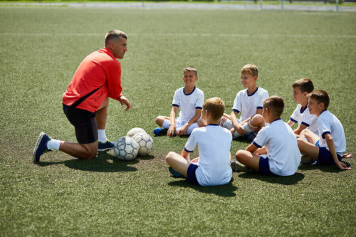 A coach helping the team in soccer practice.
