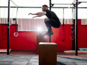 A man doing a box jump to strengthen his legs.