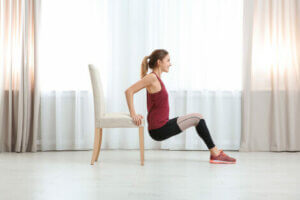 A woman using household objects to vary the intensity of her exercise at home.