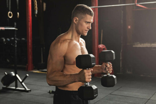 A man doing hammer curls, one of the exercises for bigger biceps.