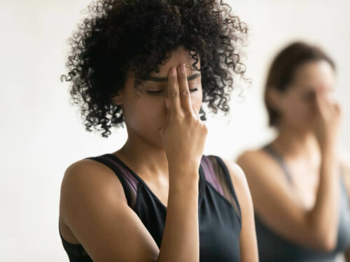 Woman with fingers on forehead, meditating to improve breathing techniques.