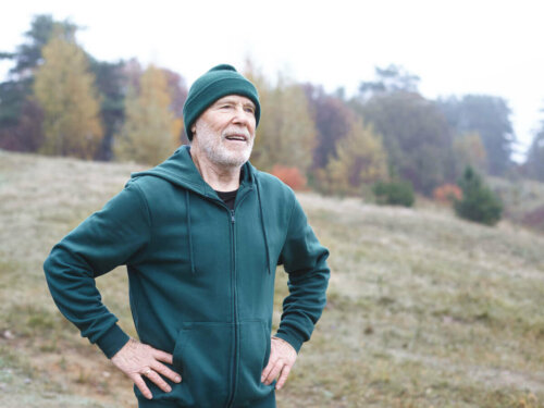 Older man running outside, stopping to breathe.