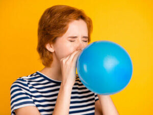 A teenager blowing up a balloon.