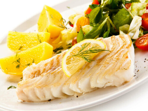 A plate of white fish and salad.