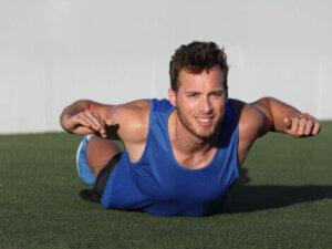 A man doing the superman plank outside.