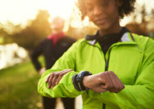 A woman on a run checking her fitness watch.