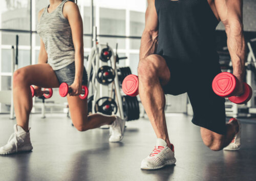 Two men at the gym performing lunge jumps.