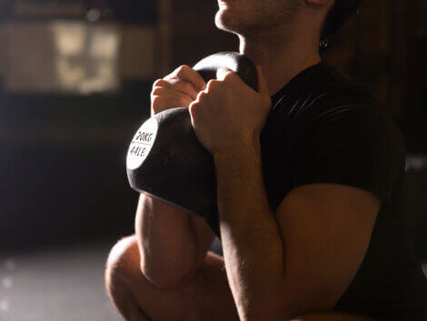 A man squatting low with a kettlebell.