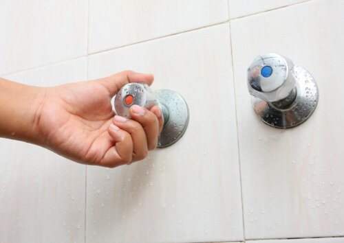 A person grabbing the shower faucet.