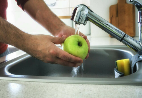 A person washing a green apple.