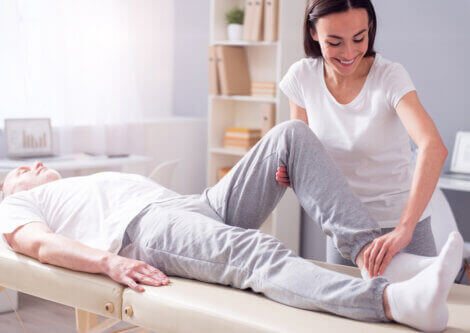 A physiotherapist helps a patient to stretch his knee.