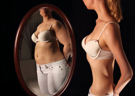 A woman looks in a mirror and sees a distorted image of herself.