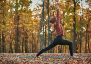 A woman doing yoga in the woods.