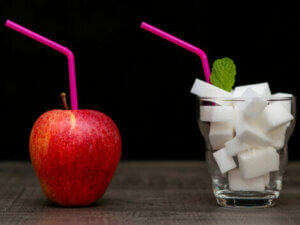 An apple and a glass filled with sugar.