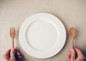 An empty plate with a fork and spoon.