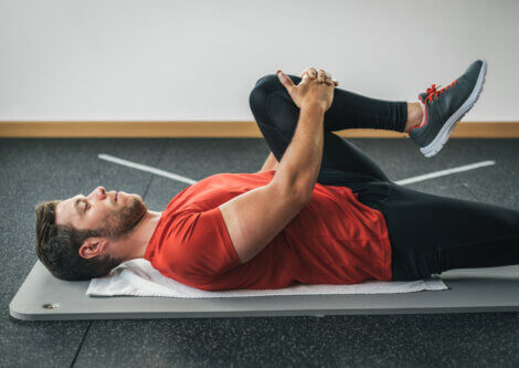 A man lying down doing glutes stretches.