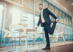 A man in a suit stretching his quadriceps.