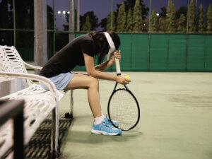A tennis player sitting down in thought.
