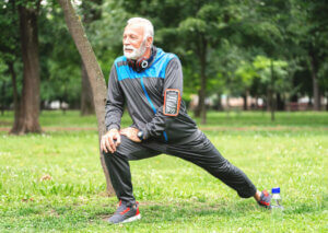 An older man stretching in the park.