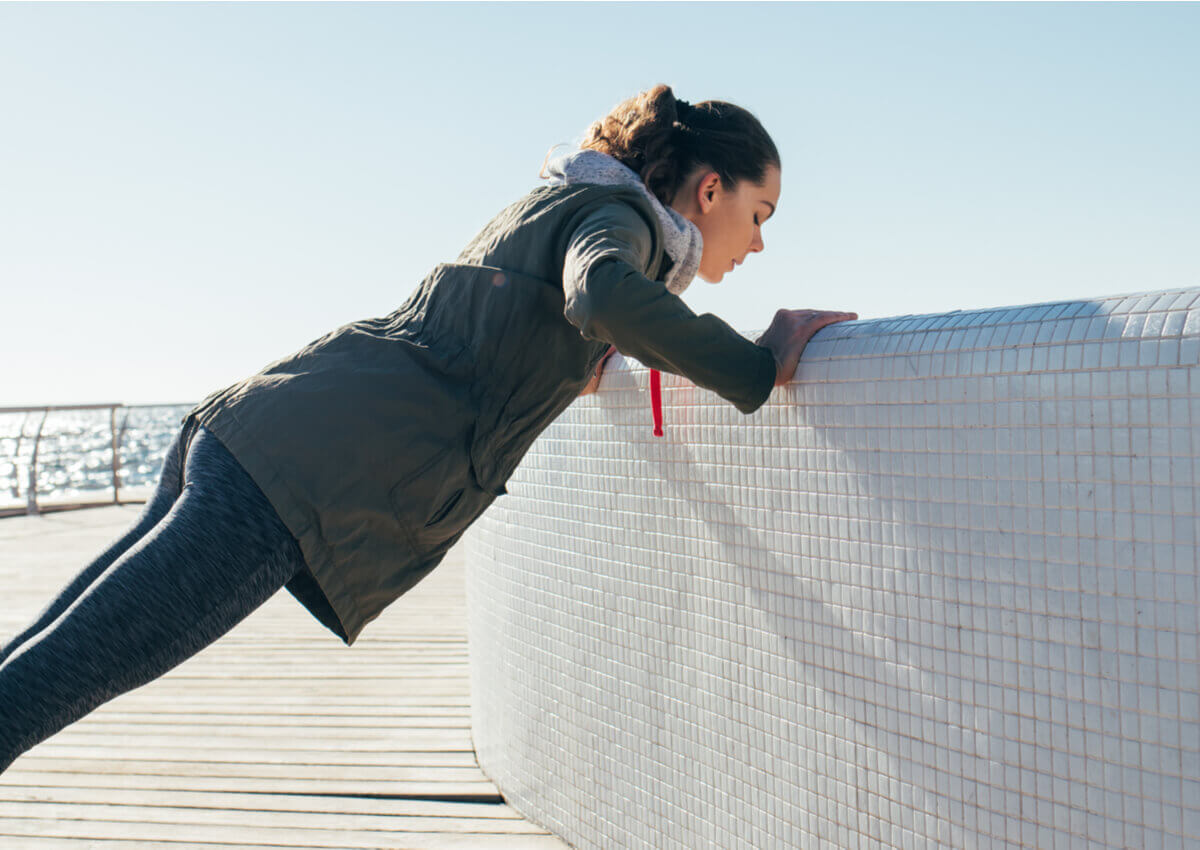 A woman doing a wall push-up.