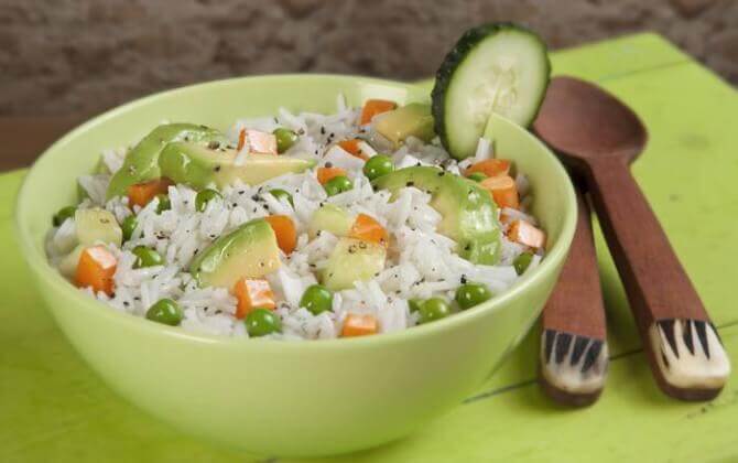 A cold rice salad with peas, carrots, and avocado.