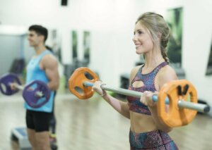 Two people lifting bar weights in a bodypump session.