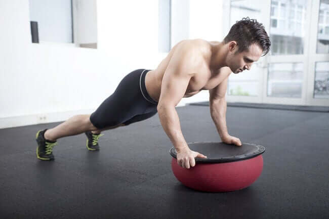 A man doing pushups on a BOSU ball.