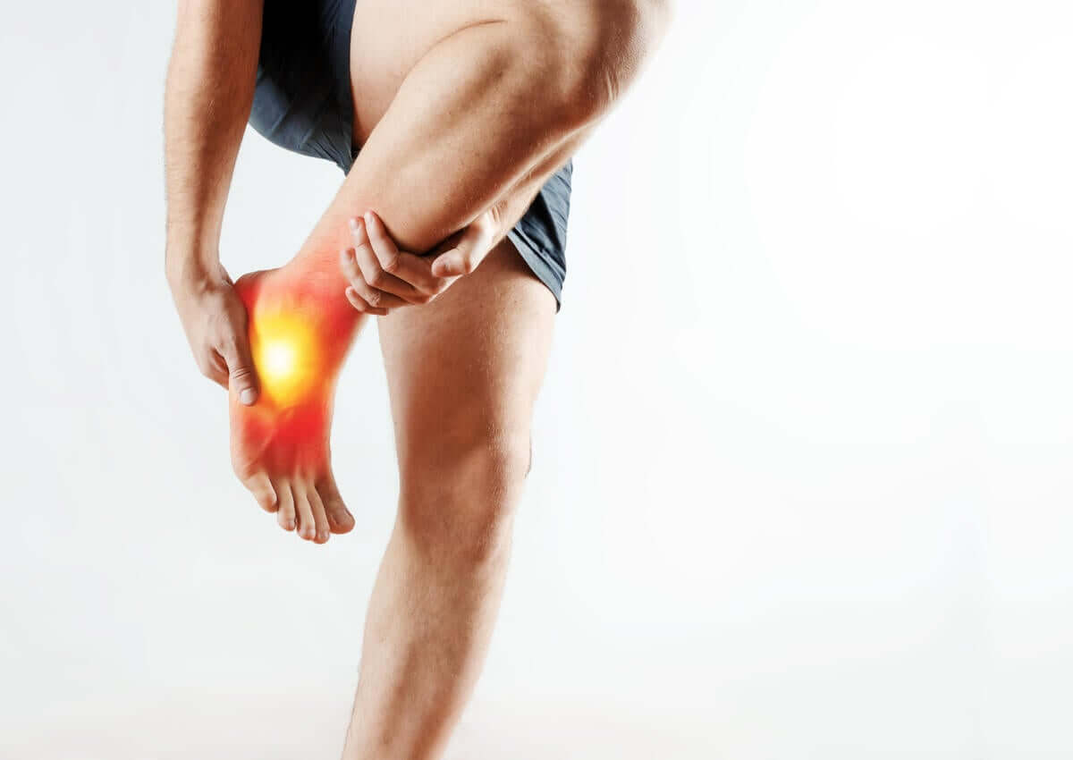 A man holding on to his painful ankle.