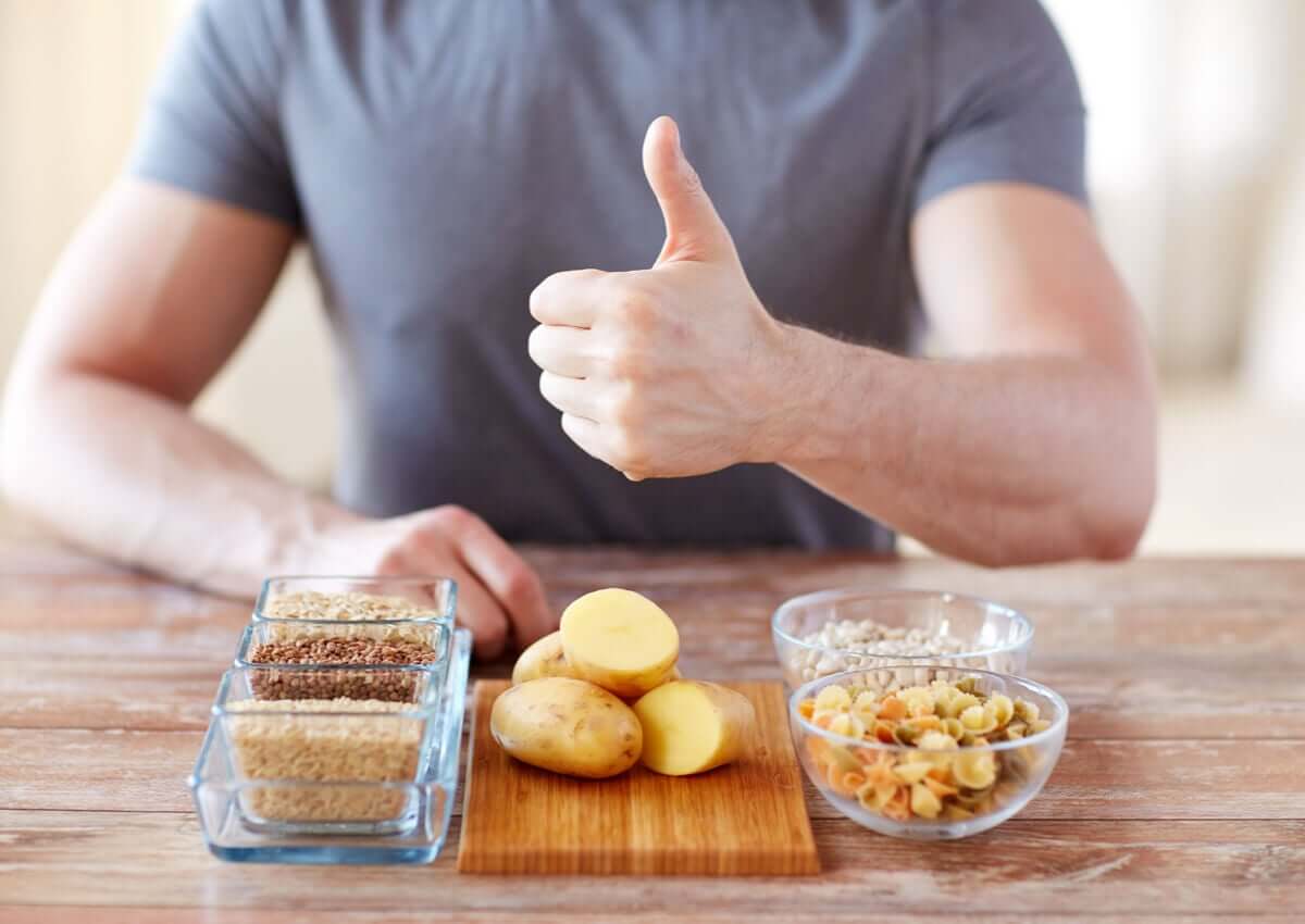 A man sitting at a table in front of a variety of carbohydrate sources.