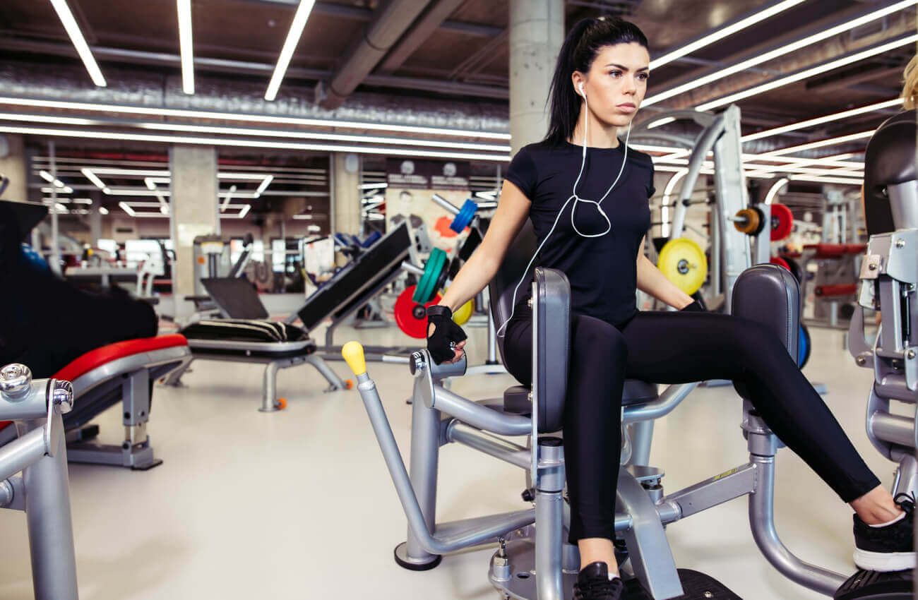 A woman using a weight machine at the gym.