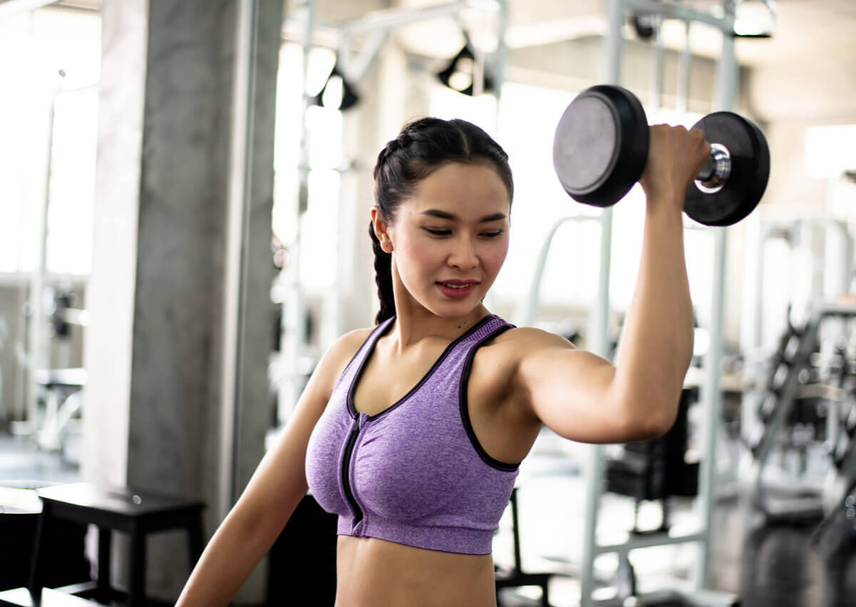 A woman lifting arm weights at the gym.